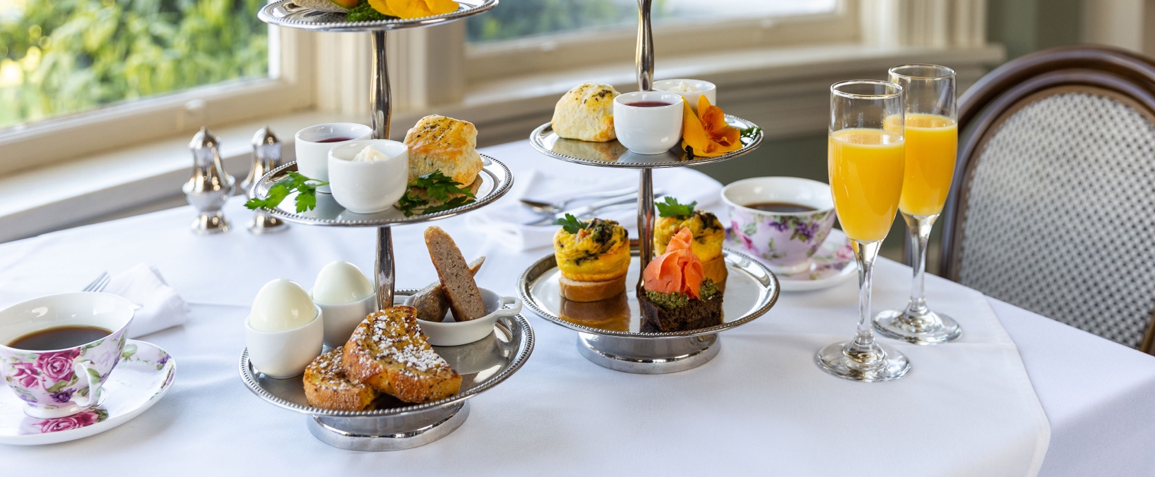 Delicious breakfast, eggs, pastries, tea and drinks on white tablecloth